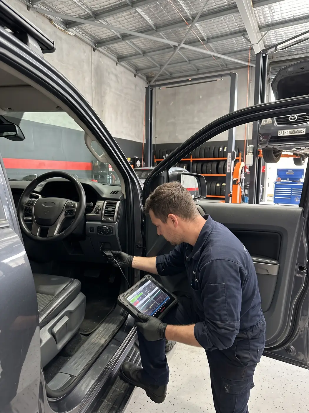 Mechanic running engine diagnostics with a scan tool inside a ute