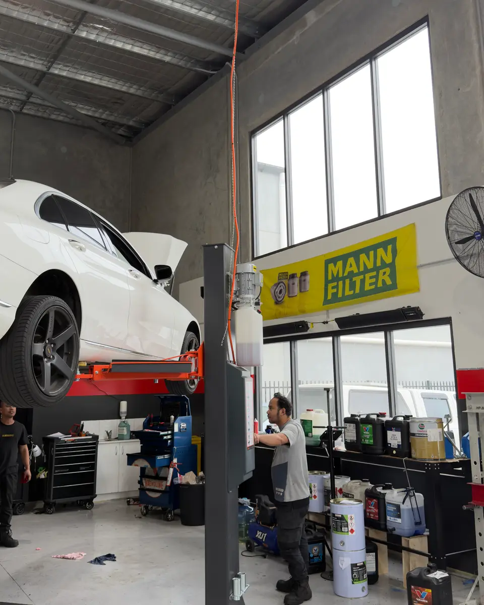 Mechanic working under a car on a hoist at SAI Motor Works Rutherford